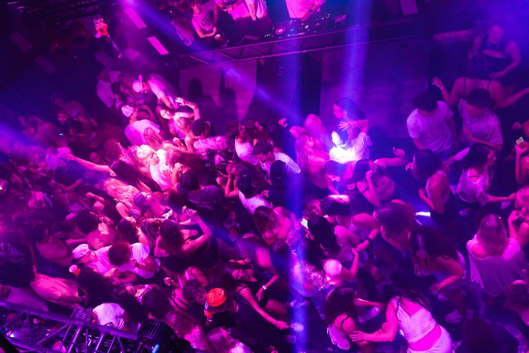 A packed floor drenched in pink light