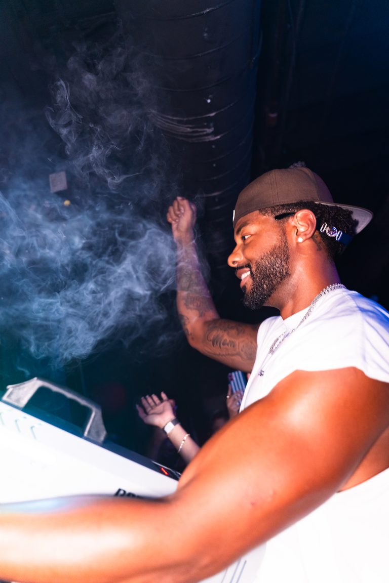 The DJ behind the decks in a drift of haze