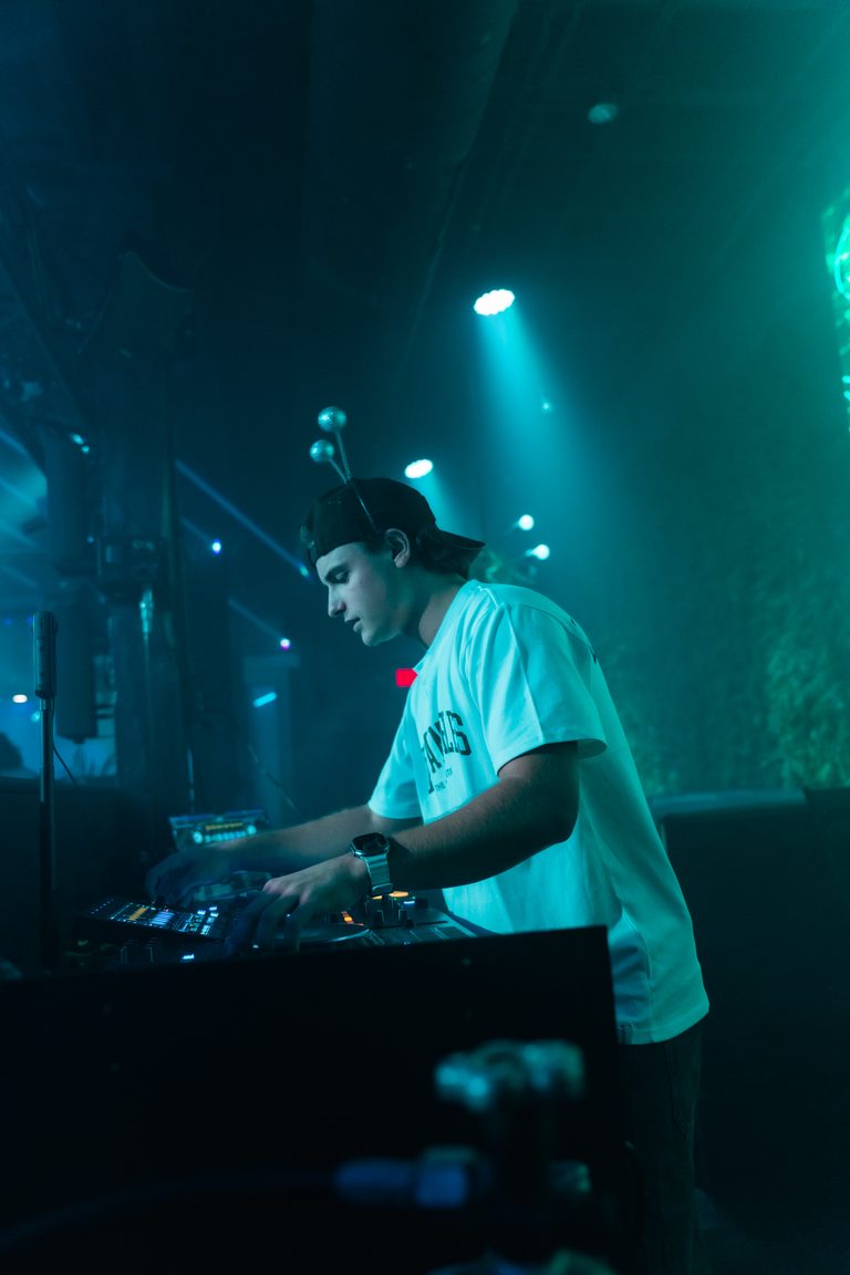 The DJ at the decks under teal beams