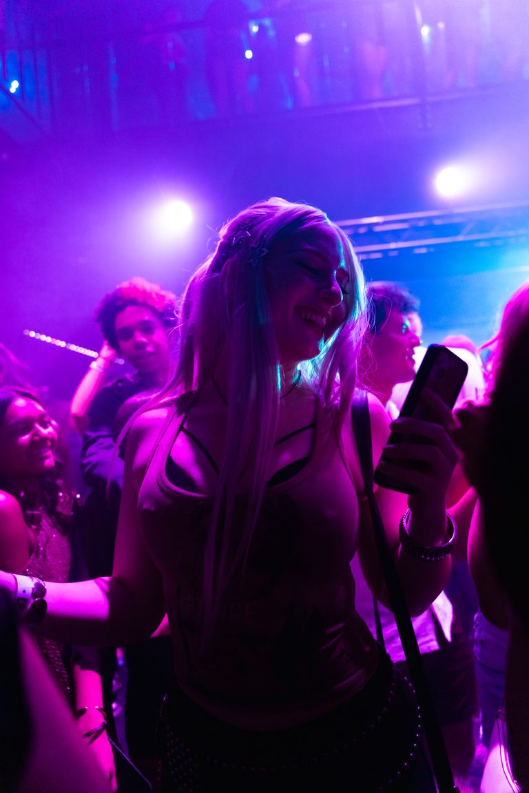 A guest dancing into purple light facing a full floor