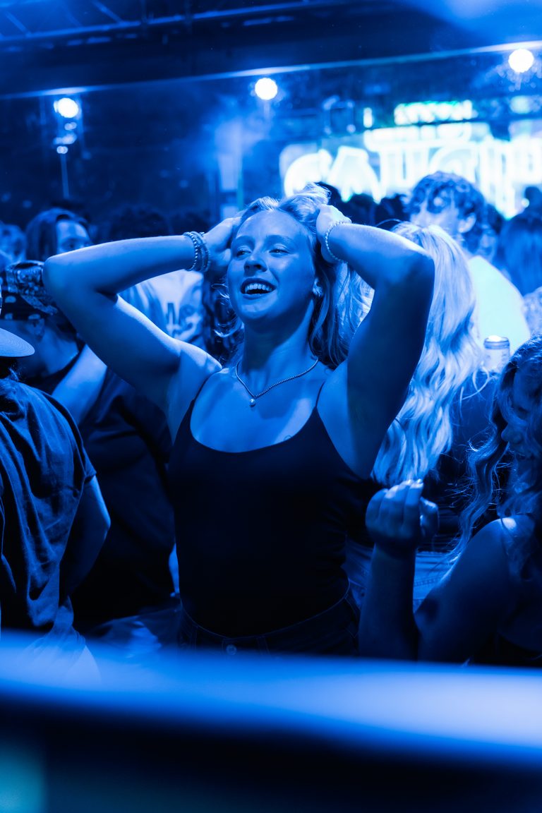 A guest with hands in her hair, eyes closed, lost in the music