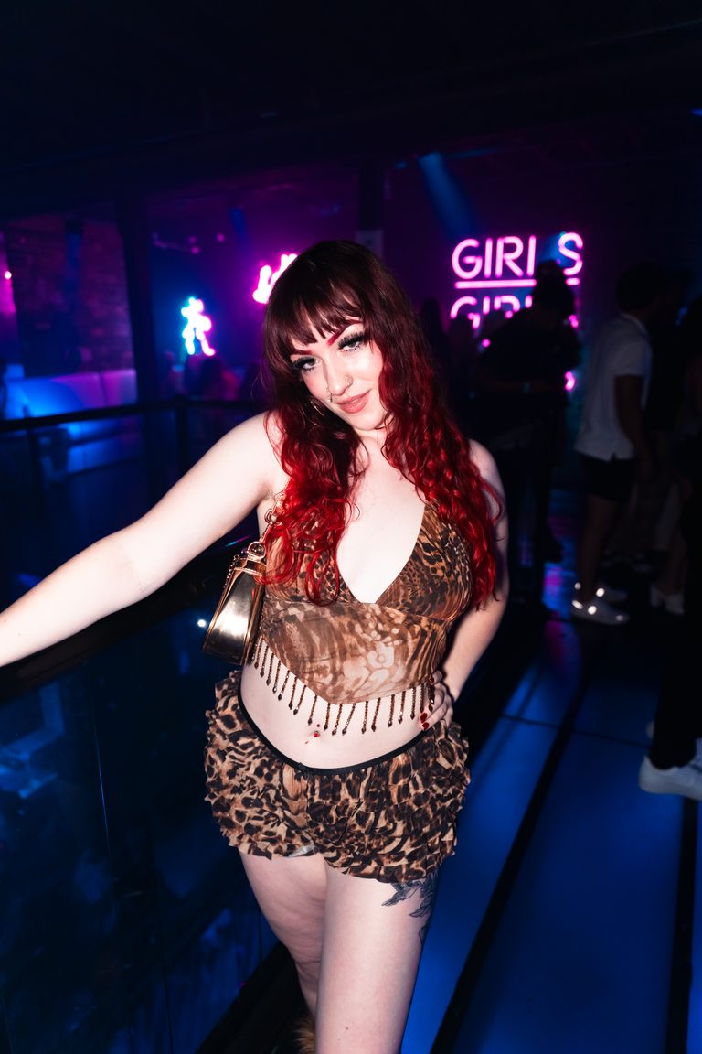 A guest at the rail with a neon sign glowing behind