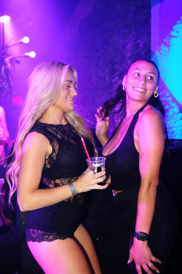 Two friends dancing together under pink light