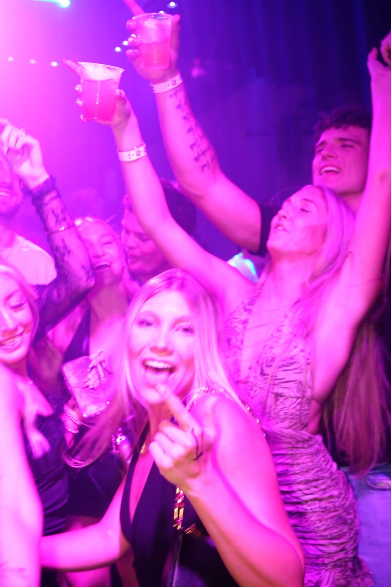 Friends with hands up on a pink-lit floor