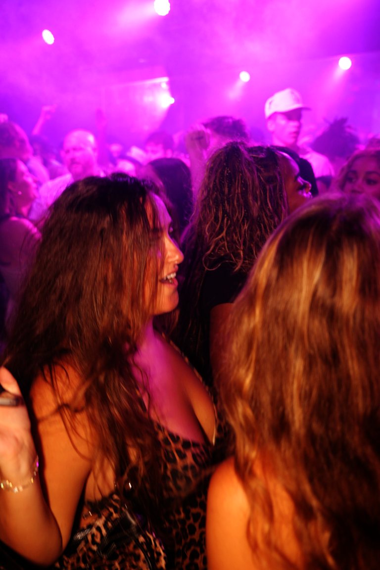 Friends dancing into pink haze on a packed floor