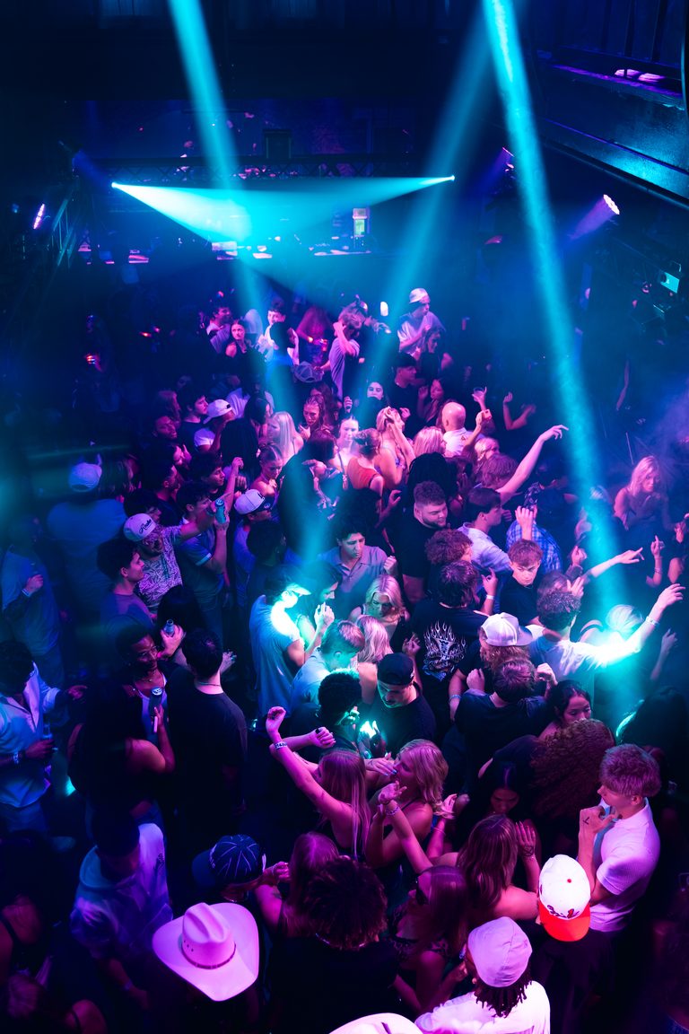 A cyan beam cluster over a full floor with hands in the air