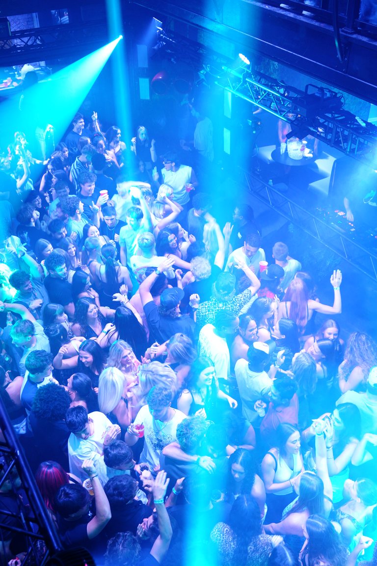 Cyan beams pouring down on the crowd, seen from above