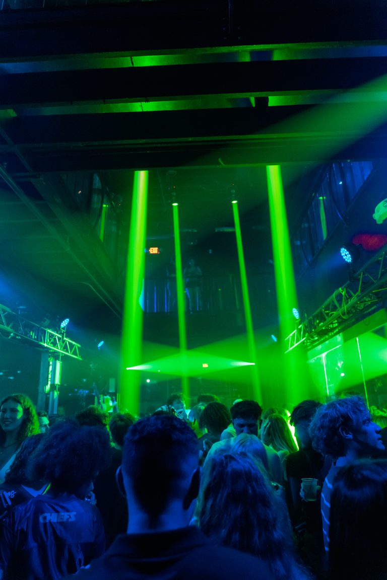 A wall of green beams behind the dance floor