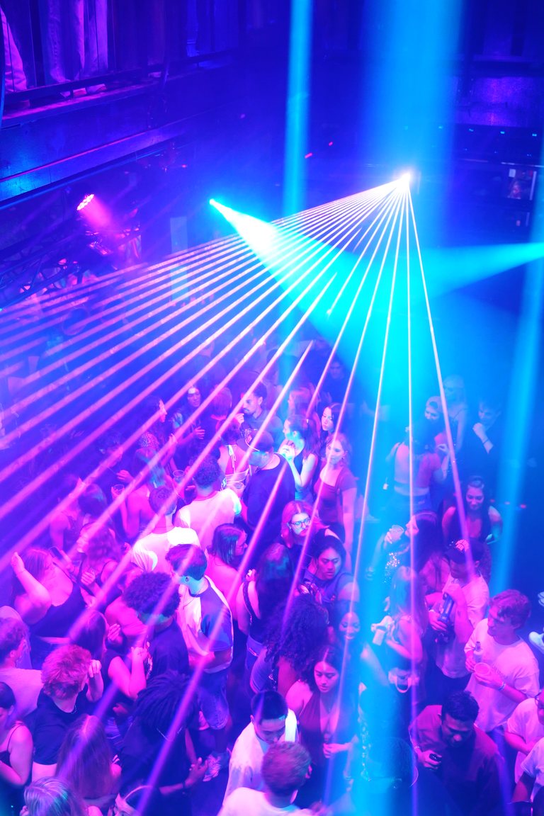 A cyan laser fan over the floor, seen from the balcony