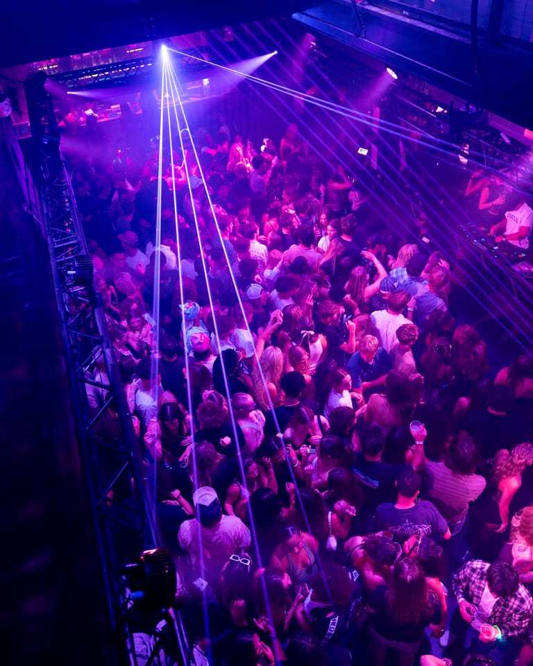 A laser fan sweeping over the dance floor, seen from the balcony