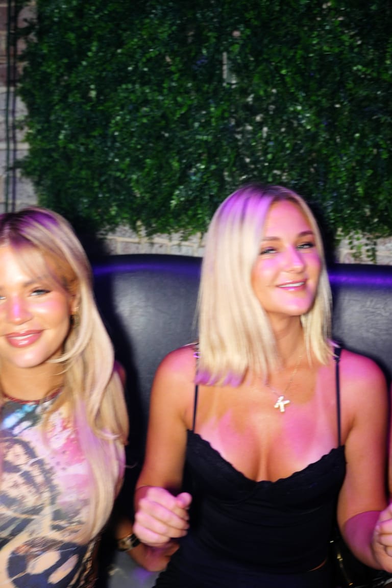 Friends dancing in their seats in a VIP booth against the greenery wall