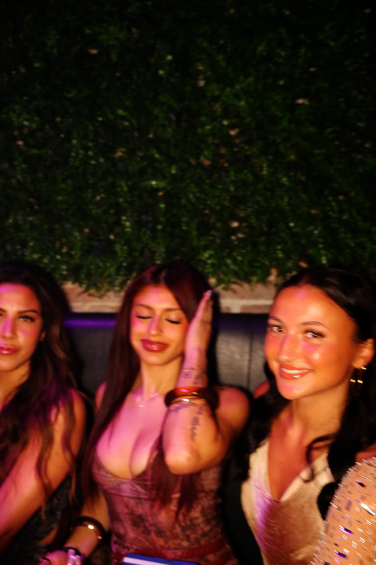 A group of friends in a VIP booth under the greenery wall