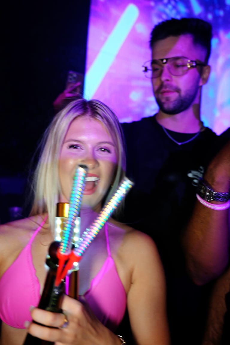 A host carrying LED sparkler wands to a VIP section